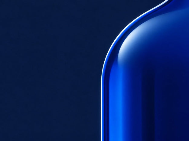 Cobalt glass bottle shoulder with a thin rim of light on deep navy