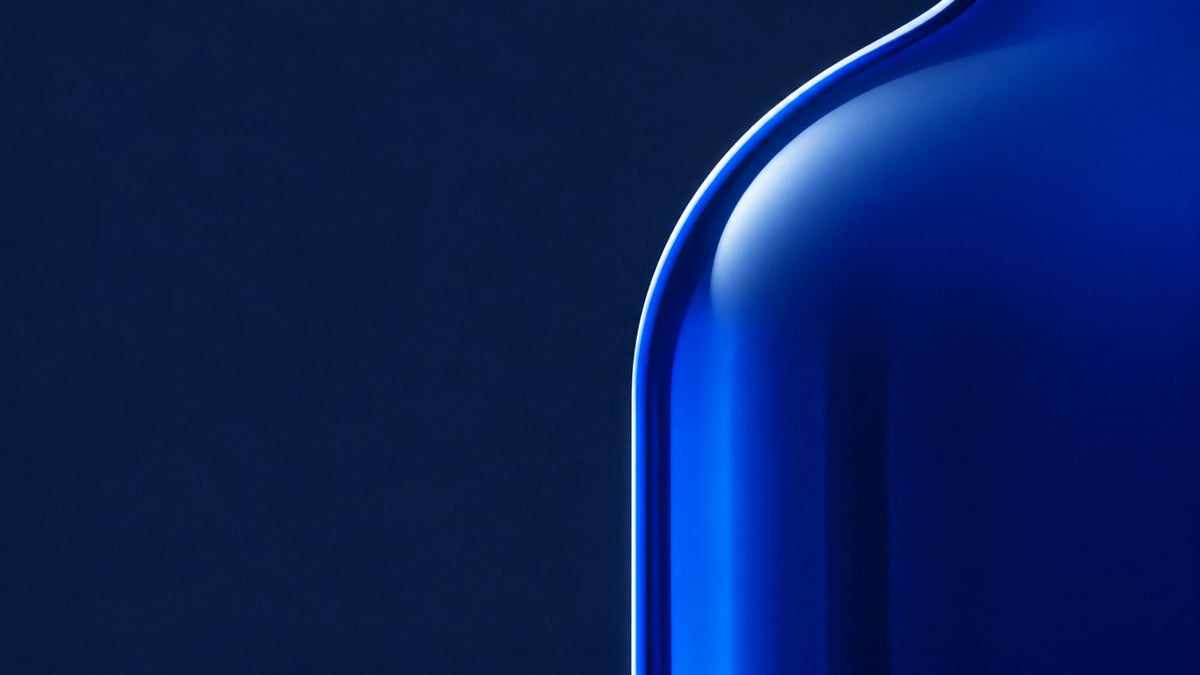 Cobalt glass bottle shoulder with a thin rim of light on deep navy